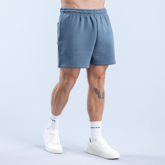 Men's denim-blue graphic shorts with side logo and elastic waistband, worn with socks