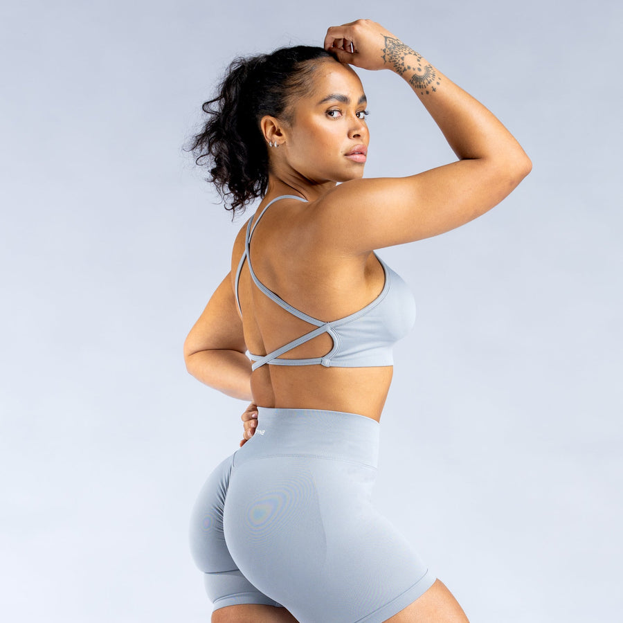 Light blue backless sports bra showing crisscross back straps and wide band