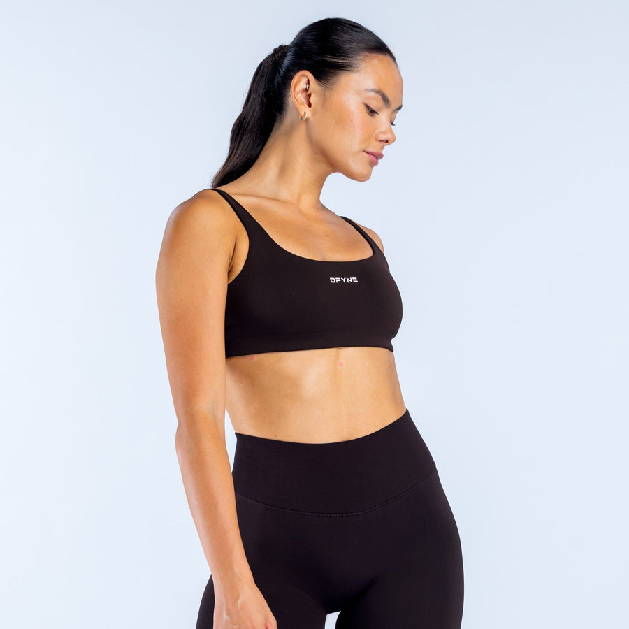 Black scoop back sports bra with scoop neckline and DPNY logo, side profile