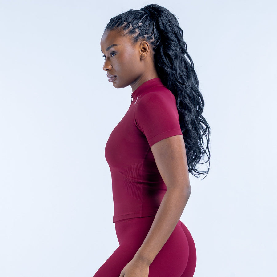 Burgundy short-sleeve zip-up athletic top, side view, fitted with front zipper