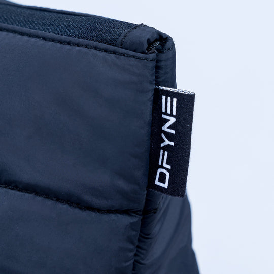 Close-up of dark navy quilted pouch with DEFY logo fabric tag