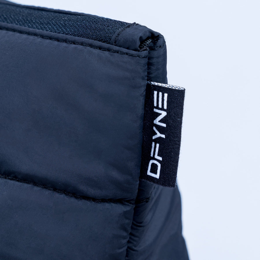 Close-up of dark navy quilted pouch with DEFY logo fabric tag