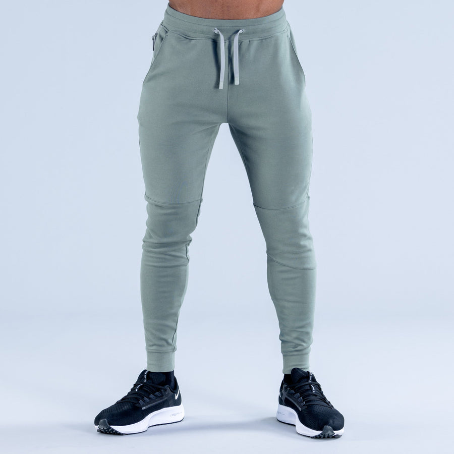 Sage green tapered jogger pants front view, drawstring waist and slanted pockets