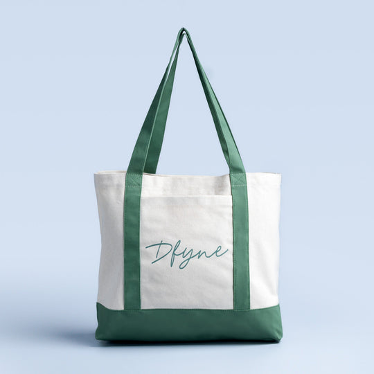Canvas tote bag with green handles and bottom, white front panel with logo print