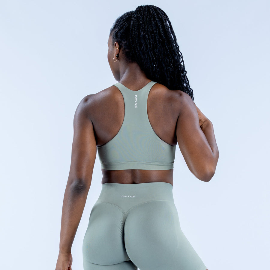 Sage green sports bra with racerback design and center back logo