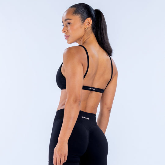 Black sports bra side view with scoop neckline and slim racerback straps