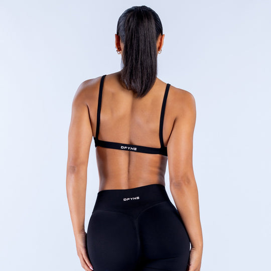Black sports bra with racerback straps and DPYNE logo on back band