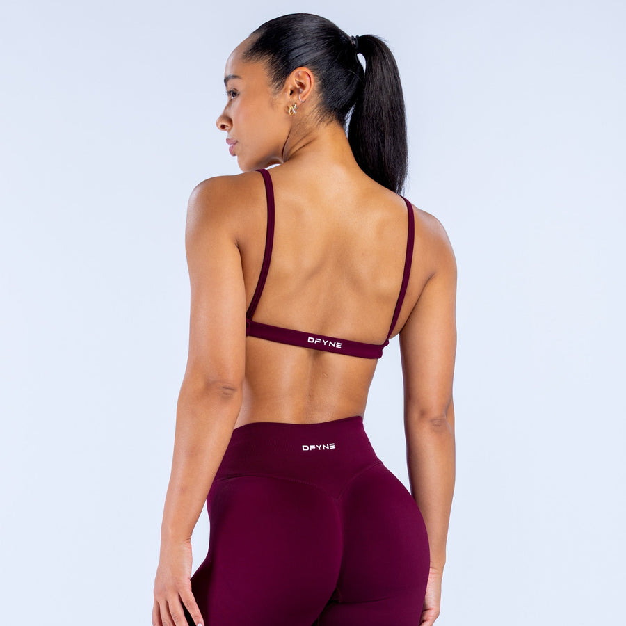 Burgundy scoop-neck sports bra shown from the back with thin straps