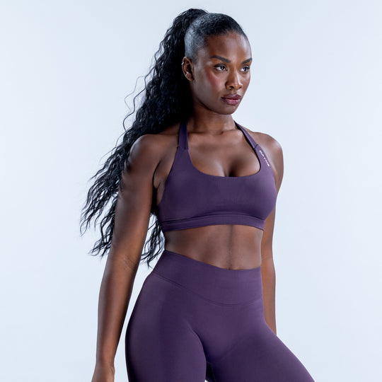 Purple impact sports bra with a scoop neckline and halter straps, shown at an angle.