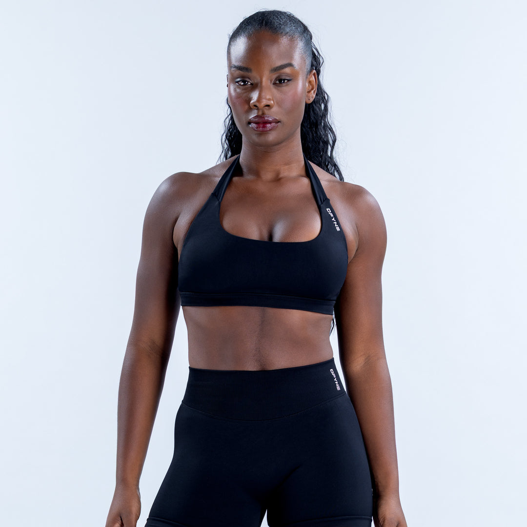 Black sports bra with a halter neckline and wide underband, shown from the front.