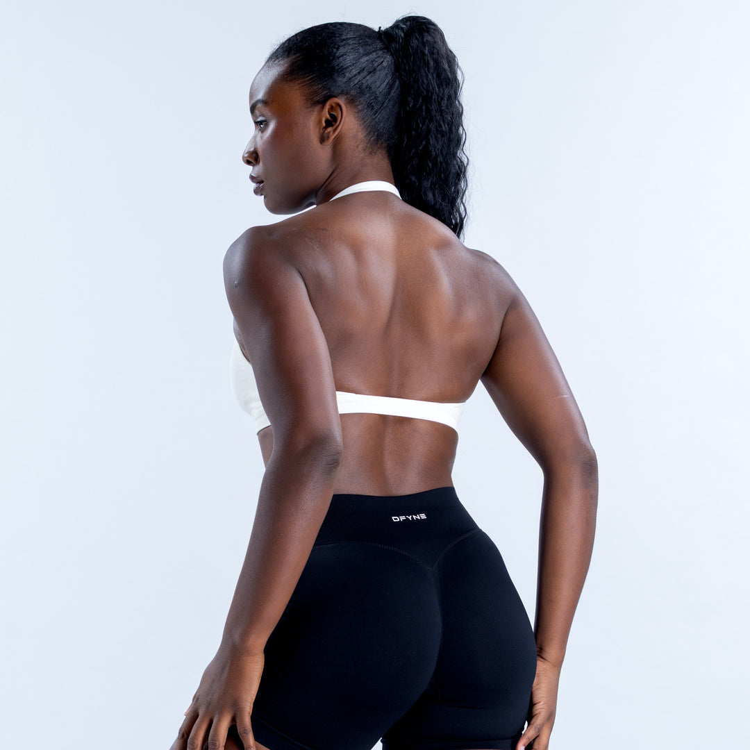 White halter sports bra shown from the back with a narrow strap across the back