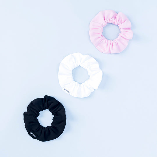 Set of three satin scrunchies in pink, white, and black with gathered centers