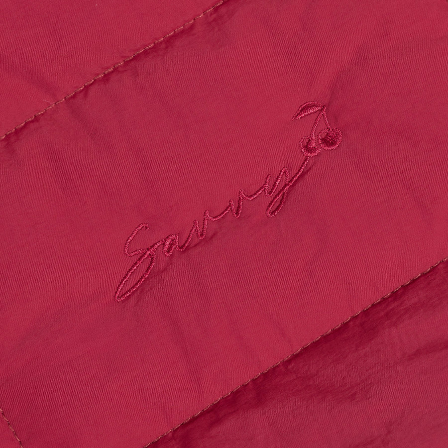 Red fabric patch with embroidered logo on quilted puffer bag.