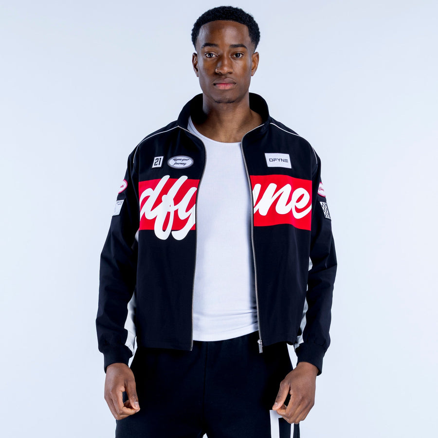 Black track jacket with stand collar and zip front, red chest band, sleeve logo patches
