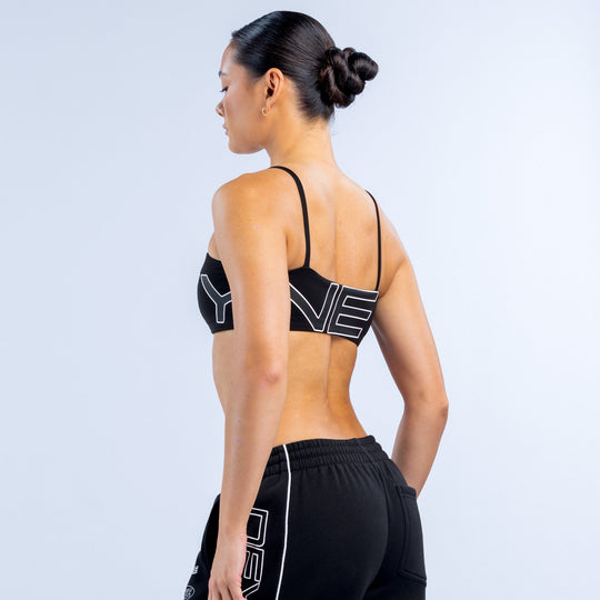 Girls' black sports bra with thin back straps and large white logo on back